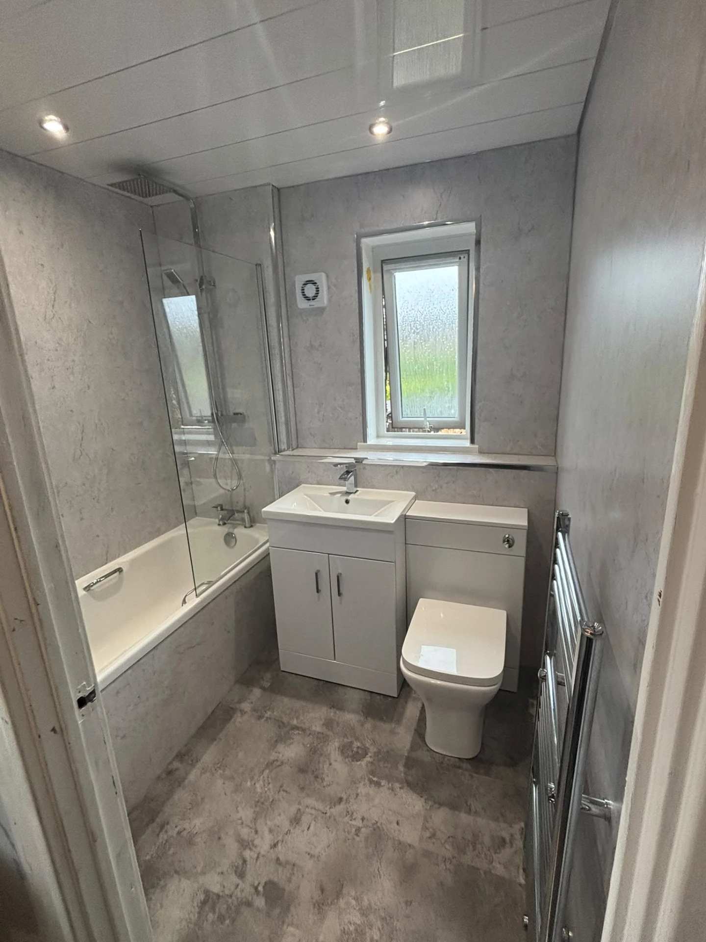 Bathroom with shower bath, white vanity, toilet and grey wall boards