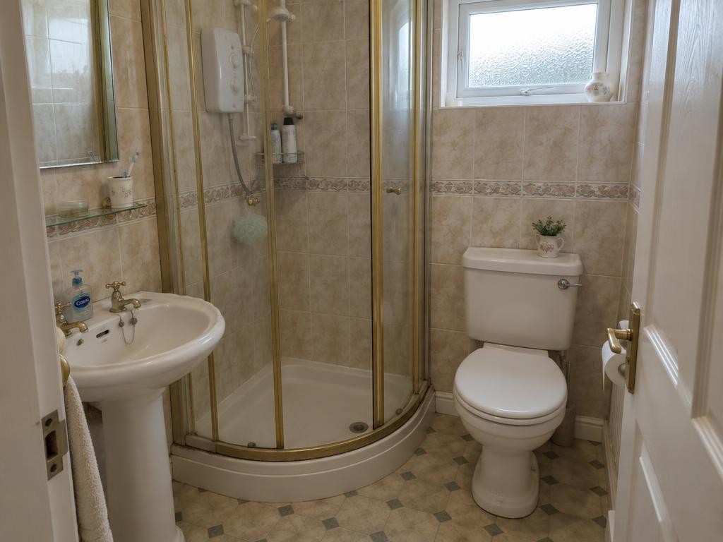 Bathroom with dated gold-framed shower cubicle before renovation